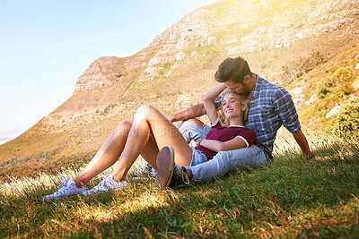 Buy stock photo Relax, kiss and happy with couple in nature for carefree, bonding and affectionate. Happiness, date and romance with man and woman cuddle in grass field for summer break, love and mountains