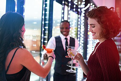 Buy stock photo Shot of a waiter serving two women cocktails at a party