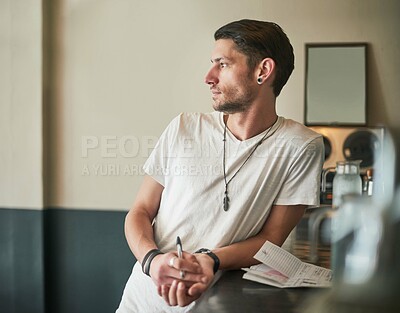 Buy stock photo Shot of a serious young bartender leaning on the bar counter