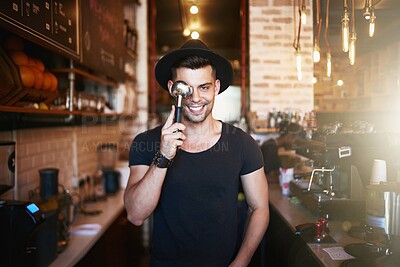 Buy stock photo Shot of a young man covering his eye with a coffee filter while working in a cafe