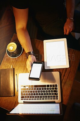 Buy stock photo Cropped high angle shot of a man using a phone and laptop while working in a coffee shop