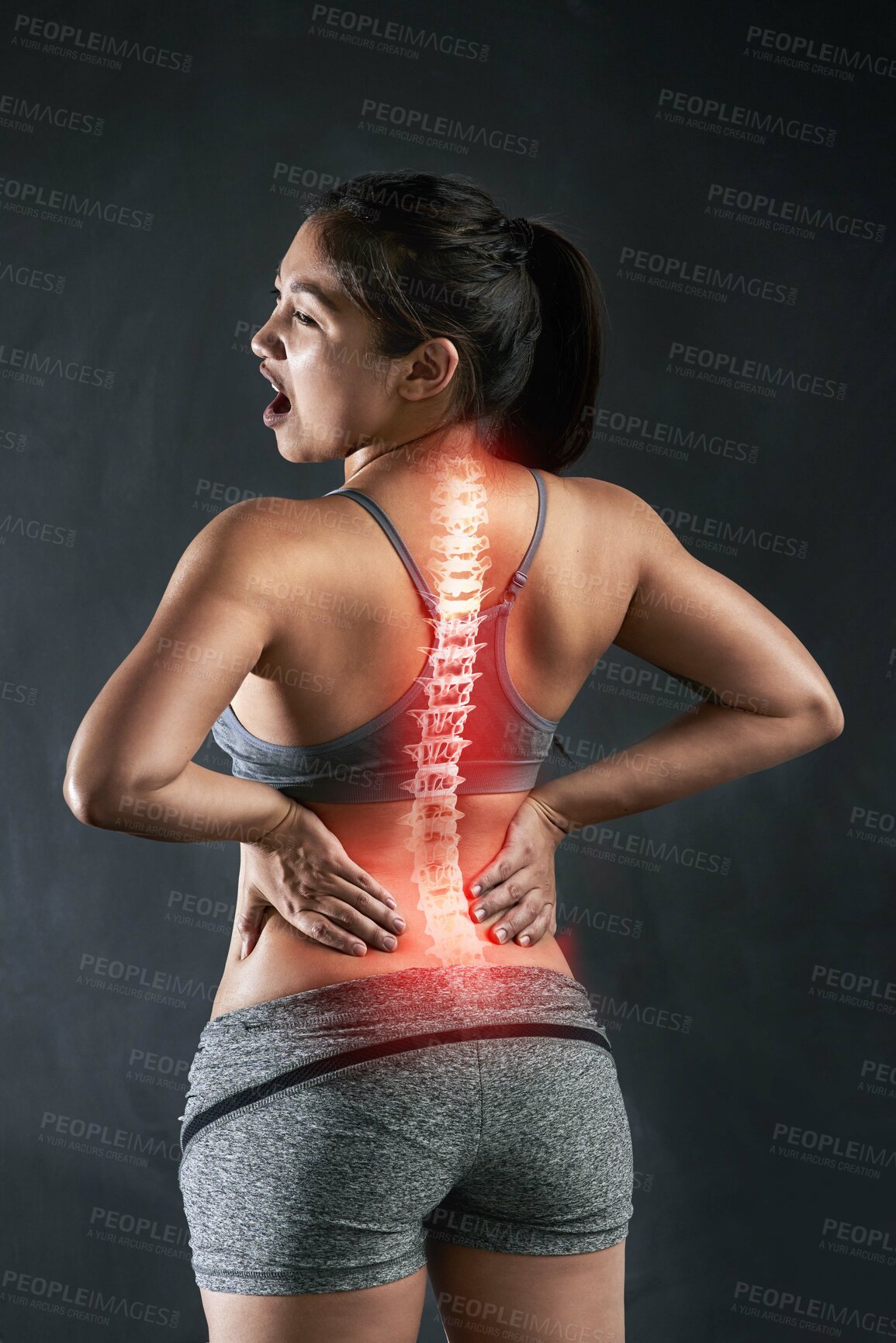 Buy stock photo Rearview shot of a young sportswoman holding her back in anguish after injuring it