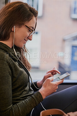 Buy stock photo Cropped shot of an attractive young woman listening to music while sitting on a bus
