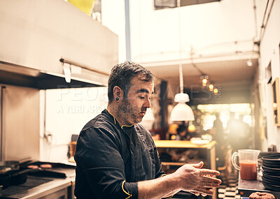 Buy stock photo Shot of a focused chef preparing a dish in the kitchen of a restaurant