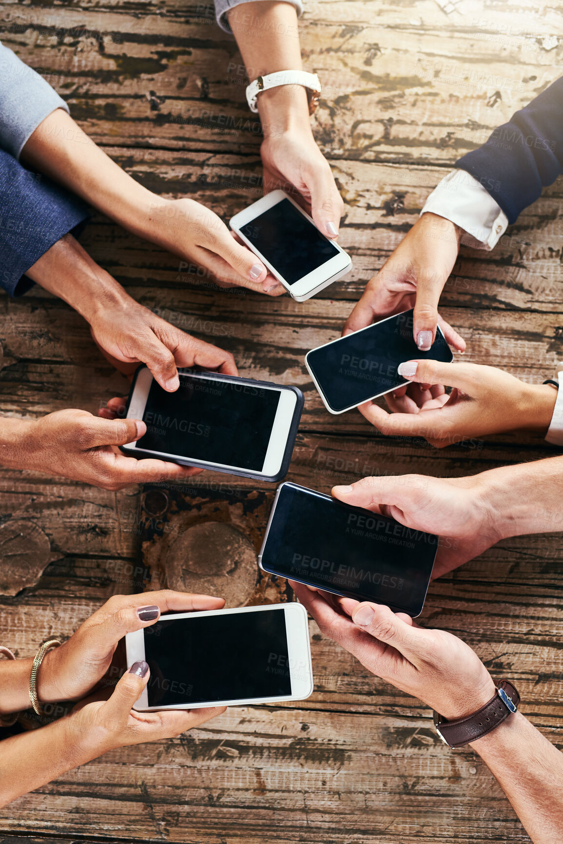 Buy stock photo High angle shot of a group of unrecognizable people browsing and texting on their cellphones while standing in a circle together