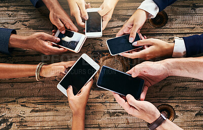 Buy stock photo High angle shot of a group of unrecognizable people browsing and texting on their cellphones while standing in a circle together