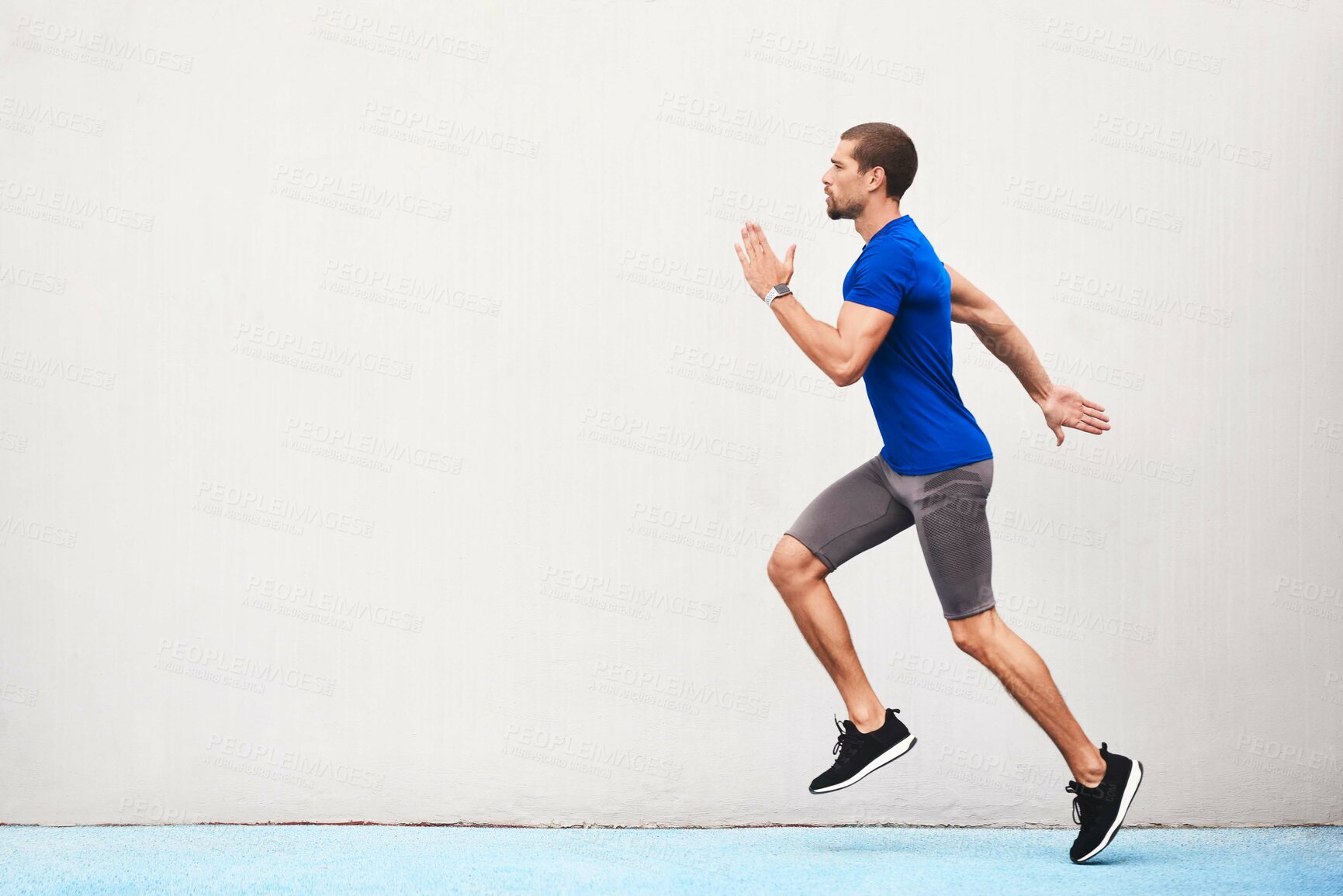 Buy stock photo Full length shot of a handsome young male athlete running along the track