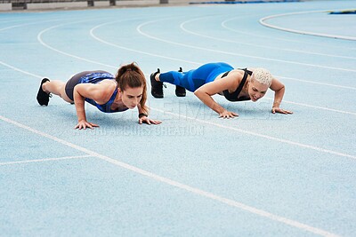 Buy stock photo Full length shot of two attractive young female athletes doing pushups out on the track