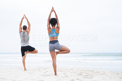 Buy stock photo Rearview shot of a young man and woman practising yoga together at the beach