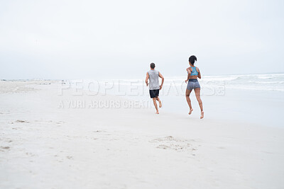 Buy stock photo Rearview shot of a young couple running along the beach together