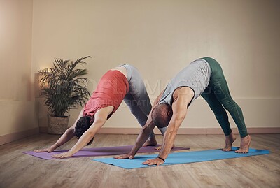 Buy stock photo Full length shot of two unrecognizable yogis holding a downward facing dog during an indoor yoga session