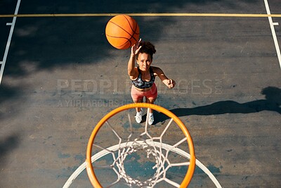 Buy stock photo High angle shot of a sporty young woman throwing a basketball into a net on a sports court