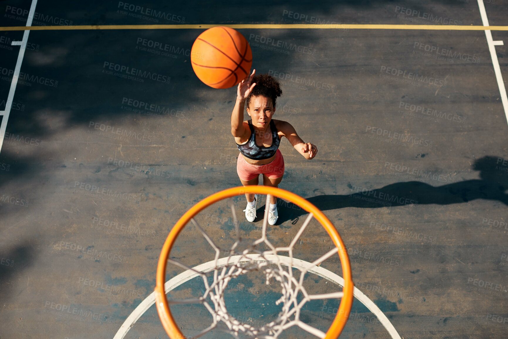 Buy stock photo High angle shot of a sporty young woman throwing a basketball into a net on a sports court