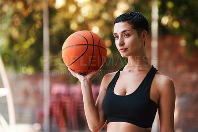 Buy stock photo Shot of a sporty young woman holding a basketball on a sports court