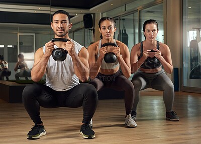 Buy stock photo Full length portrait of three young athletes working out with kettle bells in the gym