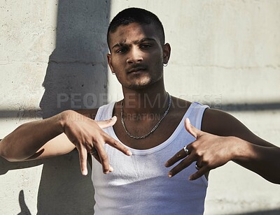 Buy stock photo Portrait of a young man showing gang signs against an urban background