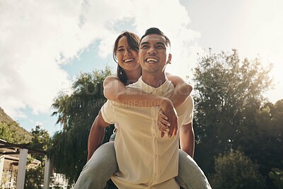 Buy stock photo Shot of a handsome young man giving his girlfriend a piggyback ride while bonding outside during the day