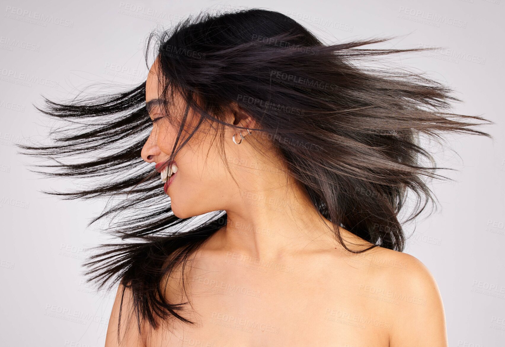 Buy stock photo Studio shot of a young woman shaking her hair while standing against a grey background