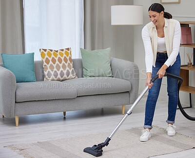 Buy stock photo Shot of a young woman vacuuming the carpet in her home