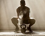 Healthy, fit and active muscular man getting ready and preparing to lift weights or a kettle bell in the gym. Male athlete exercising, training and going through his workout routine to build strength