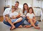 Portrait family, children smile and parents with love for kids on floor in bedroom of house together. Boy and girl siblings happy bonding with mother and father in home with happiness on weekend