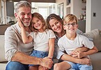 Happy, smile and portrait of a family relax in the living room bonding on the sofa together. Happiness, care and parents sitting and holding their children with love on a lounge couch at home