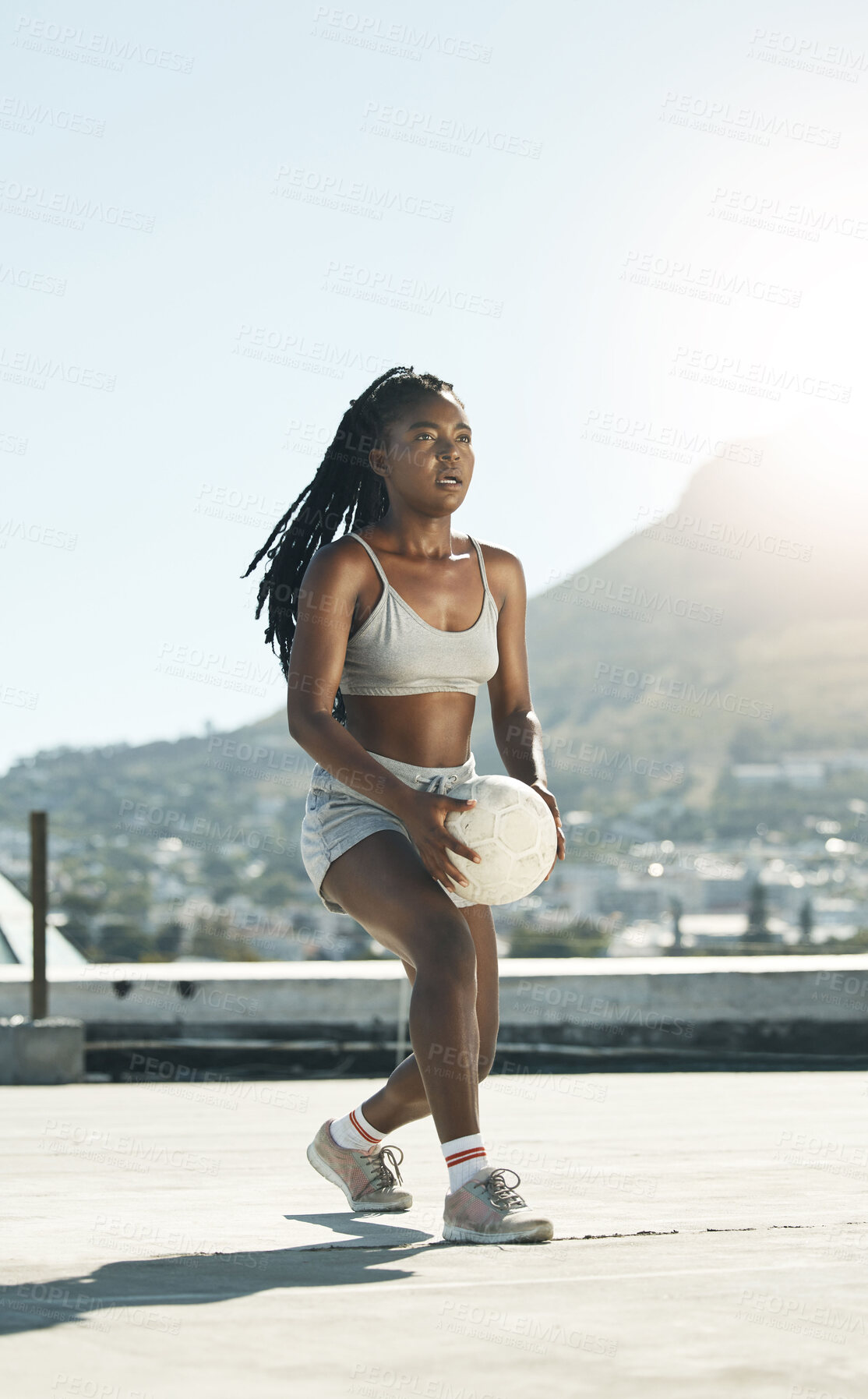 Buy stock photo City, girl and soccer on rooftop for sports fitness training with concentration in South Africa. Exercise, football and black woman holding ball for cardio practice with mountain cityscape.

