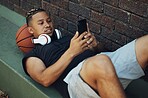 Basketball player, phone and fitness app on break after sports match, game or practice with ball and black man outdoor. Male fitness athlete with 5g network on social media after sport and exercise 