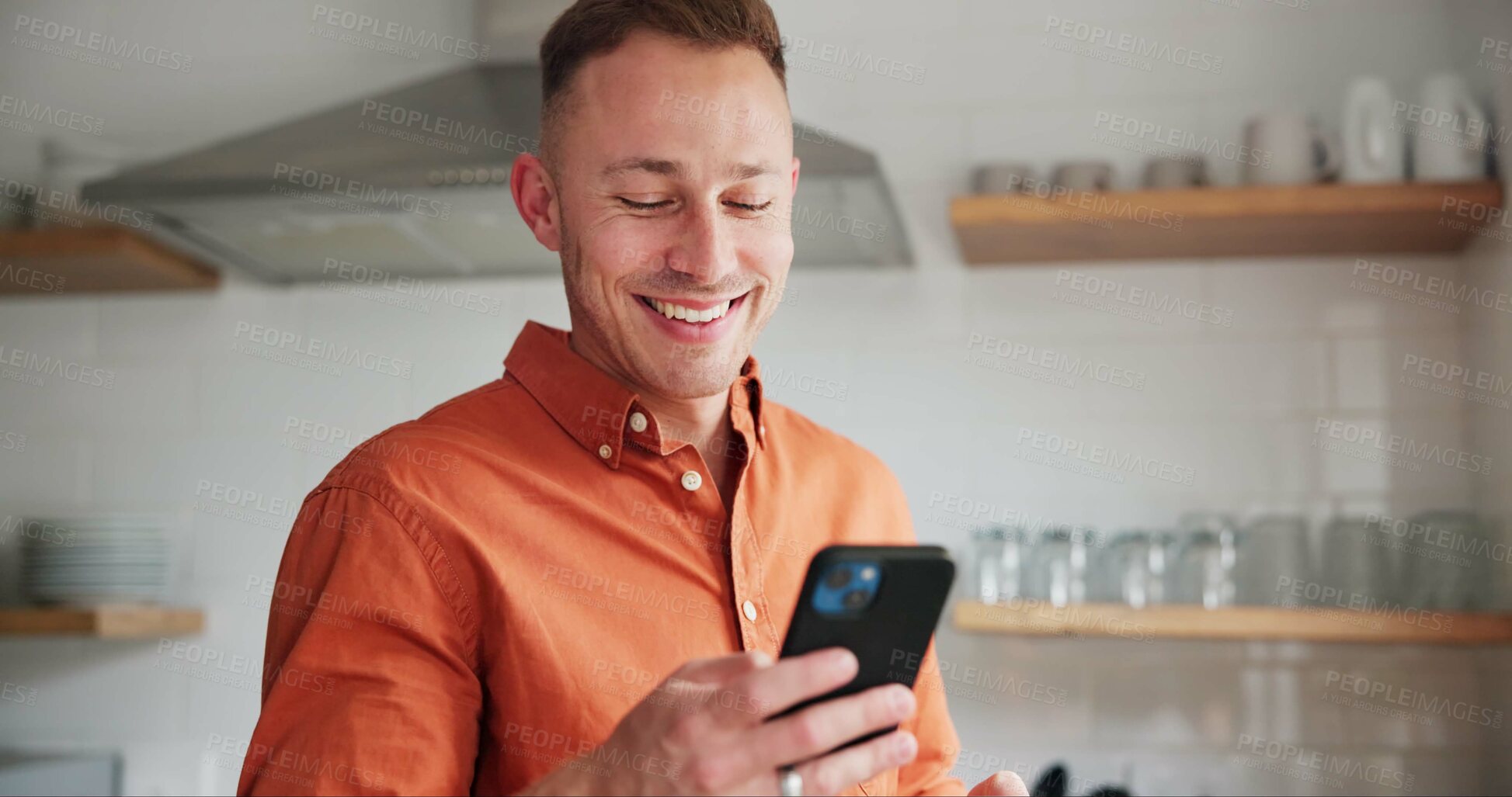 Buy stock photo Man, kitchen and typing on phone or browsing social media at home, happy and relaxing on weekend. Happy male person, communication and mobile application for online conversation, humor and laughing