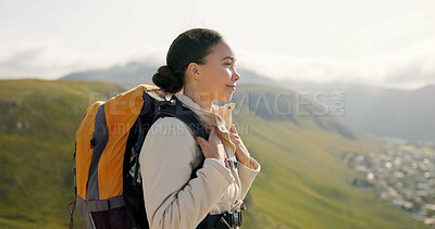 Young woman, trekking on mountains and breathing fresh air for outdoor wellness, fitness and health. Happy person in wind with backpack and hiking in nature on a hill for adventure, travel or journey