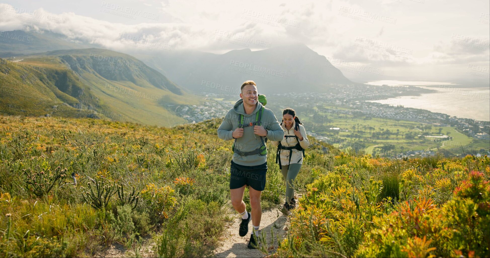 Buy stock photo Couple of friends walking, hiking on mountain and travel for fitness, adventure or journey in nature for wellness. Young people trekking with backpack on a path or green hill for cardio and health