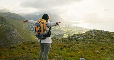 Woman, mountain top and freedom or celebration of hiking goals, travel or trekking adventure in nature. Back of person or winner in backpack and arms up for success, achievement or excited on a cliff