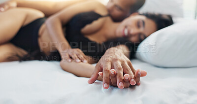 Happy couple, relax and holding hands on bed for love, morning or romance in embrace, trust or care at home. Young man and woman smile lying in bedroom for intimacy, passion or bonding at house