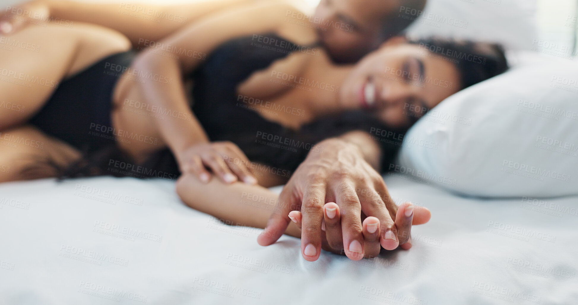 Buy stock photo Happy couple, relax and holding hands on bed for love, morning or romance in embrace, trust or care at home. Young man and woman smile lying in bedroom for intimacy, passion or bonding at house