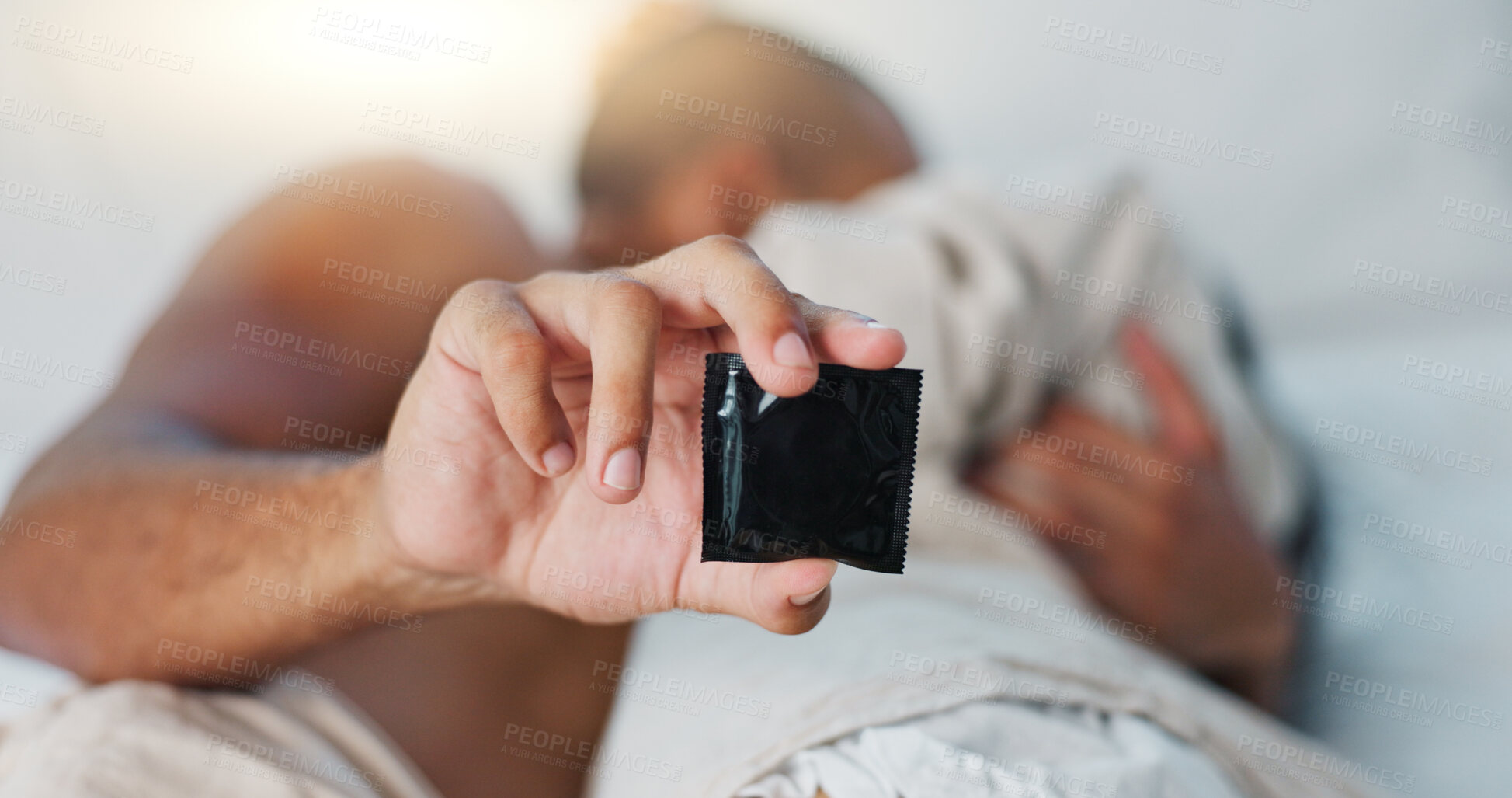 Buy stock photo Hand, condom and people in bed for sex, protection and contraception with lust and desire on Valentines day. Intimacy, health and safety for couple bonding in bedroom with rubber and sexual moment