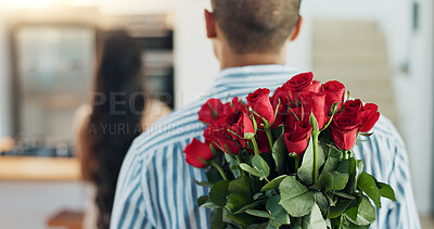 Happy couple, red roses and kiss for surprise, anniversary or valentines day in kitchen at home. Face of young man and woman smile with flowers for romantic gift, love or care in celebration at house