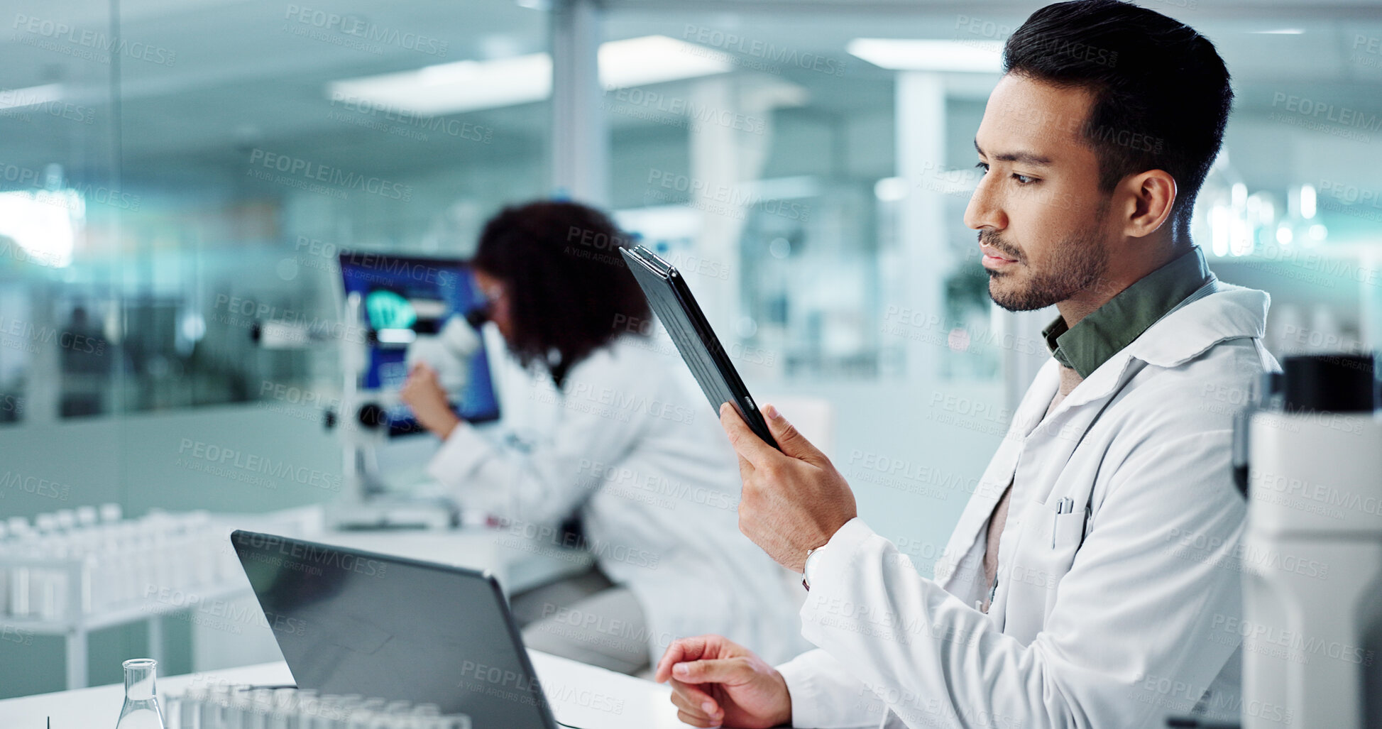 Buy stock photo Scientist, thinking on computer and tablet for laboratory research, DNA analysis and results in medical study at night. Young man of science and biotechnology, digital software or laptop for solution