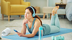 Smartphone, yoga and headphones of woman typing on chat app for fitness communication, social media update or blog writing wellness. Pilates girl with exercise gear and technology in home living room