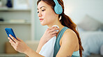 Woman, phone and yoga with rest, towel and music while sitting, floor and relax in living room. Girl, headphone and smartphone for streaming, video or reading while taking break, training or fitness