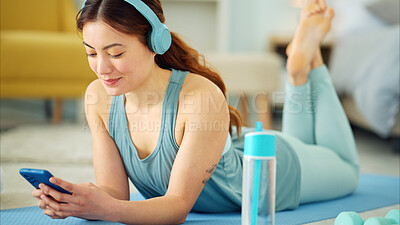 Smartphone, yoga and headphones of woman typing on chat app for fitness communication, social media update or blog writing wellness. Pilates girl with exercise gear and technology in home living room