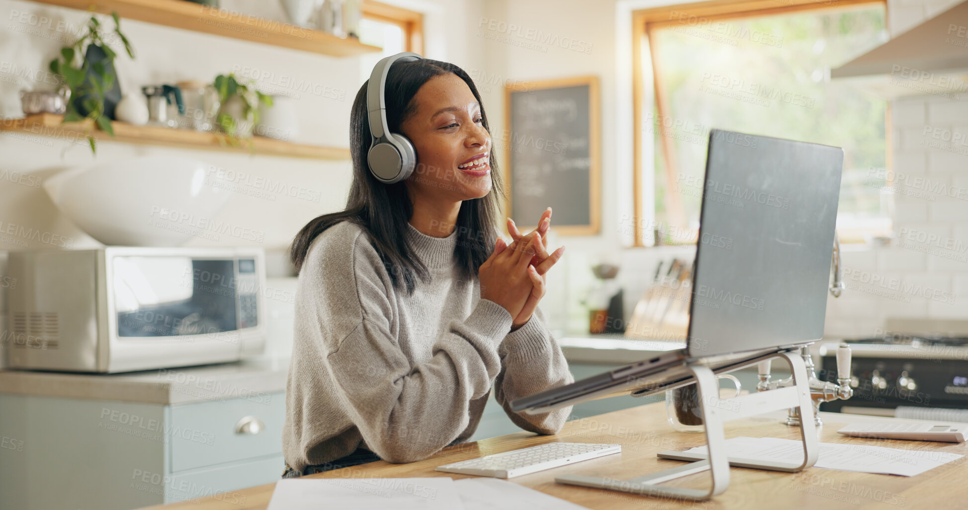 Buy stock photo Laptop, headphones and video call with a woman entrepreneur in the kitchen of her home for small business. Computer, virtual meeting and a young freelance employee remote working from her house