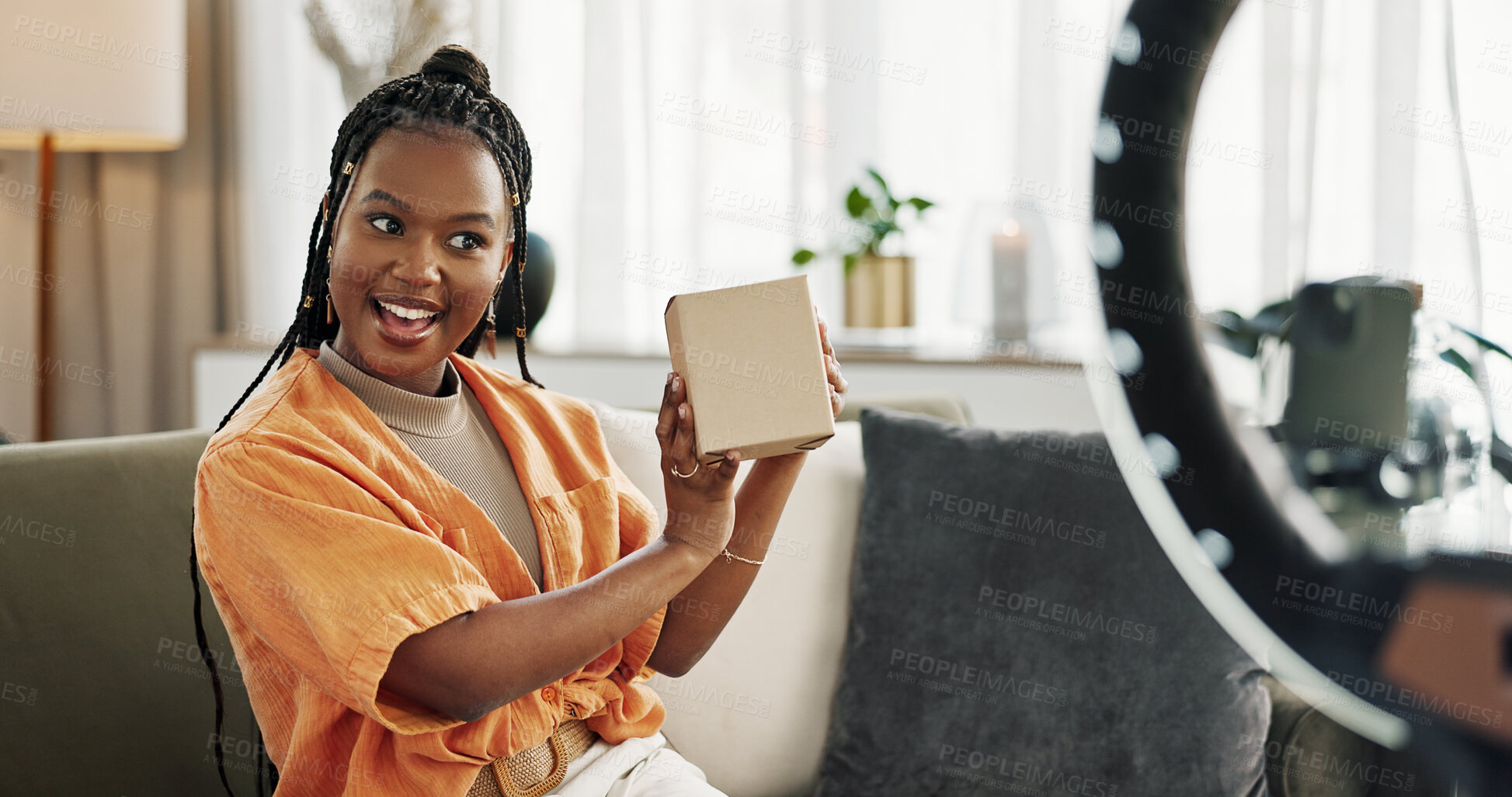 Buy stock photo Wave, live streaming and happy black woman with box or product in home living room. Hello, influencer and person with package, record video on social media and content creation, ring light and phone