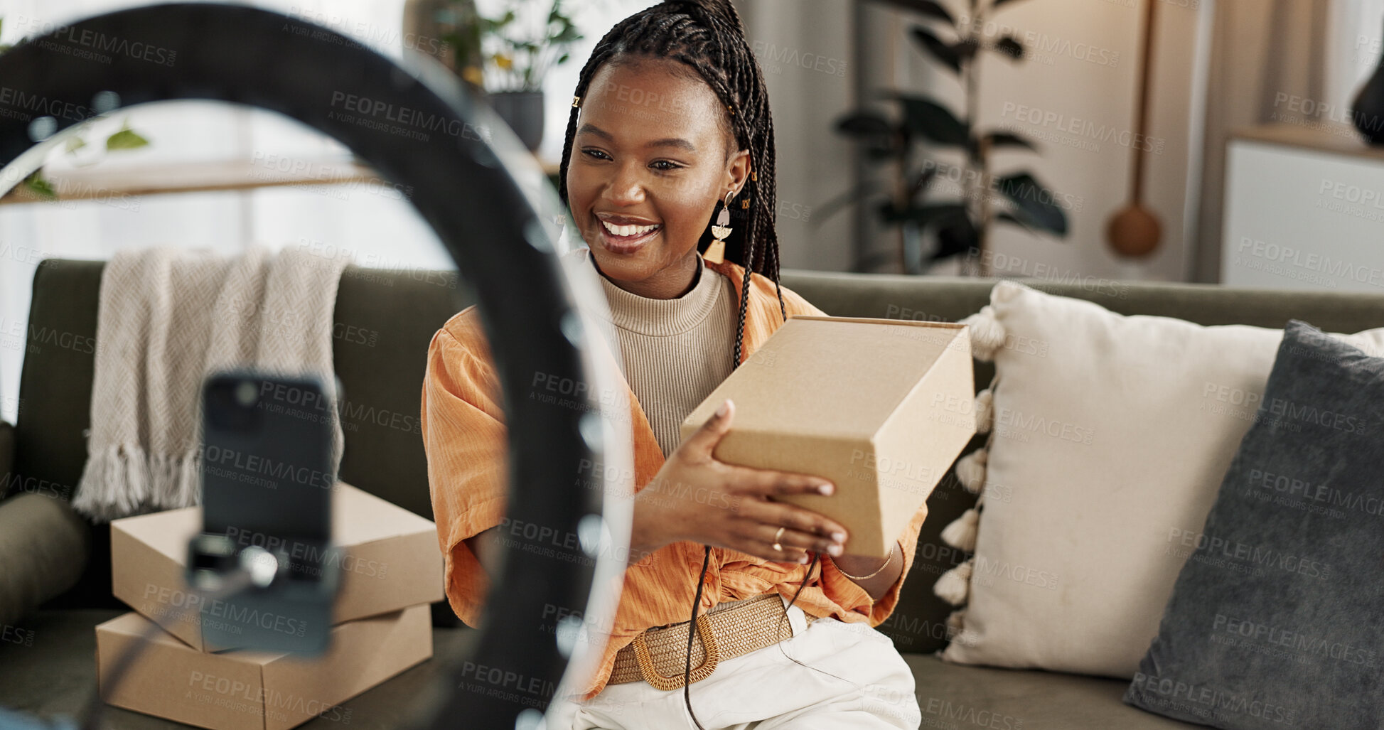 Buy stock photo Influencer, live streaming and happy black woman with box or product in home living room. Hello, influencer and person with package, record video on social media and content creation, ring light and phone