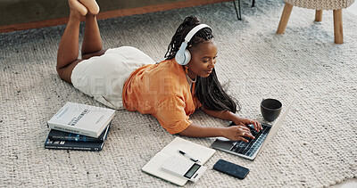 Laptop, headphones and young woman on the floor in living room of modern apartment. Tech, smile and young African female university student study and listen to music on computer in lounge at home.