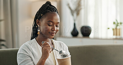 Black woman on sofa, eating ice cream and relax in living room with smile, summer pleasure and enjoy. Happiness, fun or thinking, girl on couch with taste of frozen chocolate getalo dessert in home.