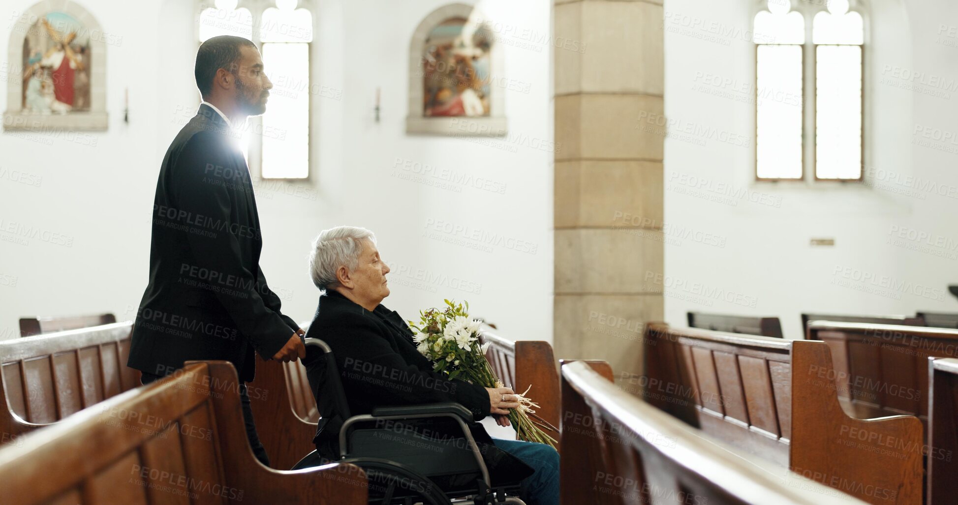 Buy stock photo Senior, woman and wheelchair at memorial service with flowers for death, mourning and widow with man. Family, grief and help person with disability at chapel for bereavement, burial ceremony and loss
