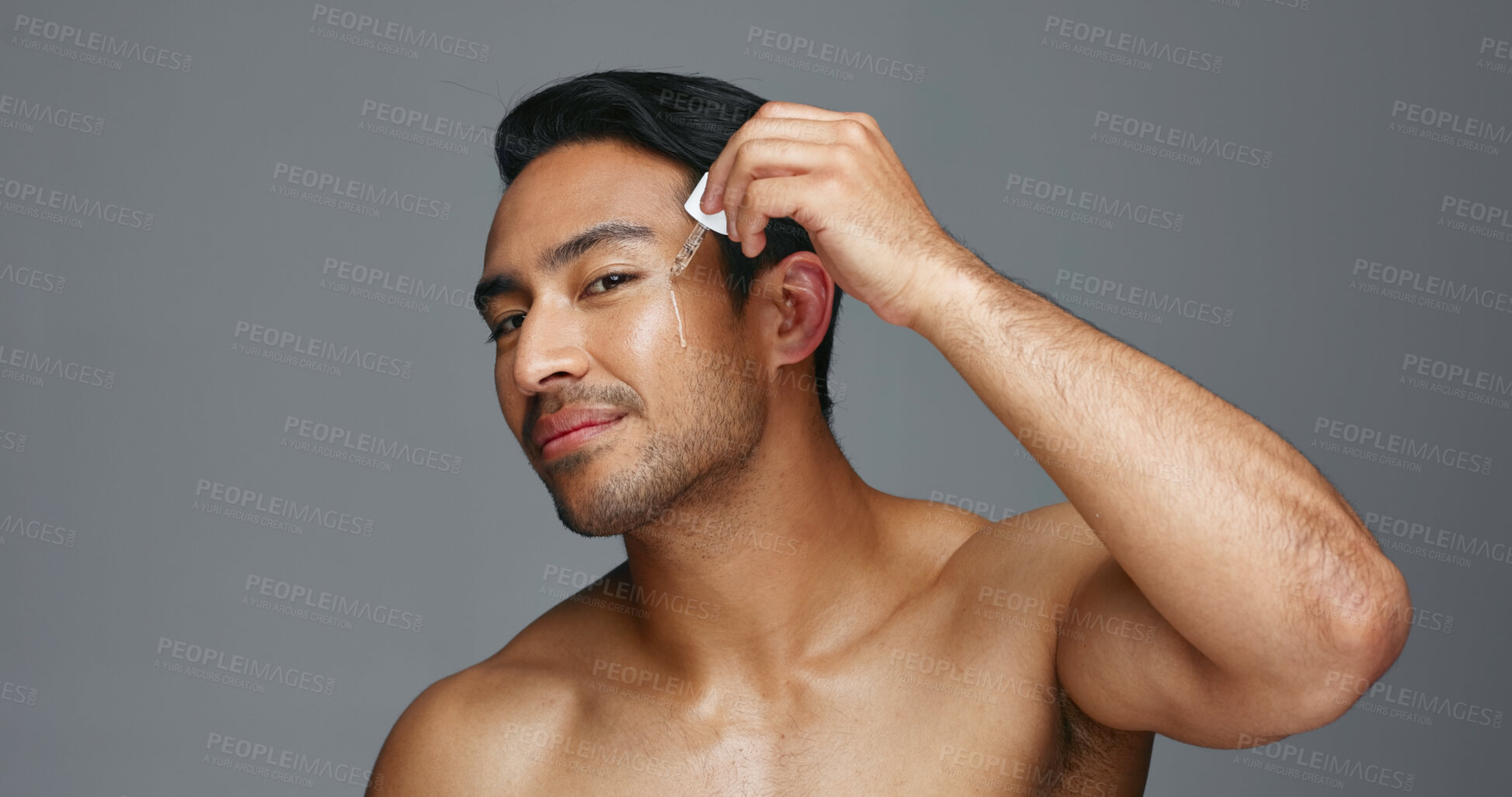 Buy stock photo Man, face and essential oil for beauty, skincare and cosmetics product on a gray, studio background. Young asian person in portrait with facial serum, dermatology dropper or collagen for skin care