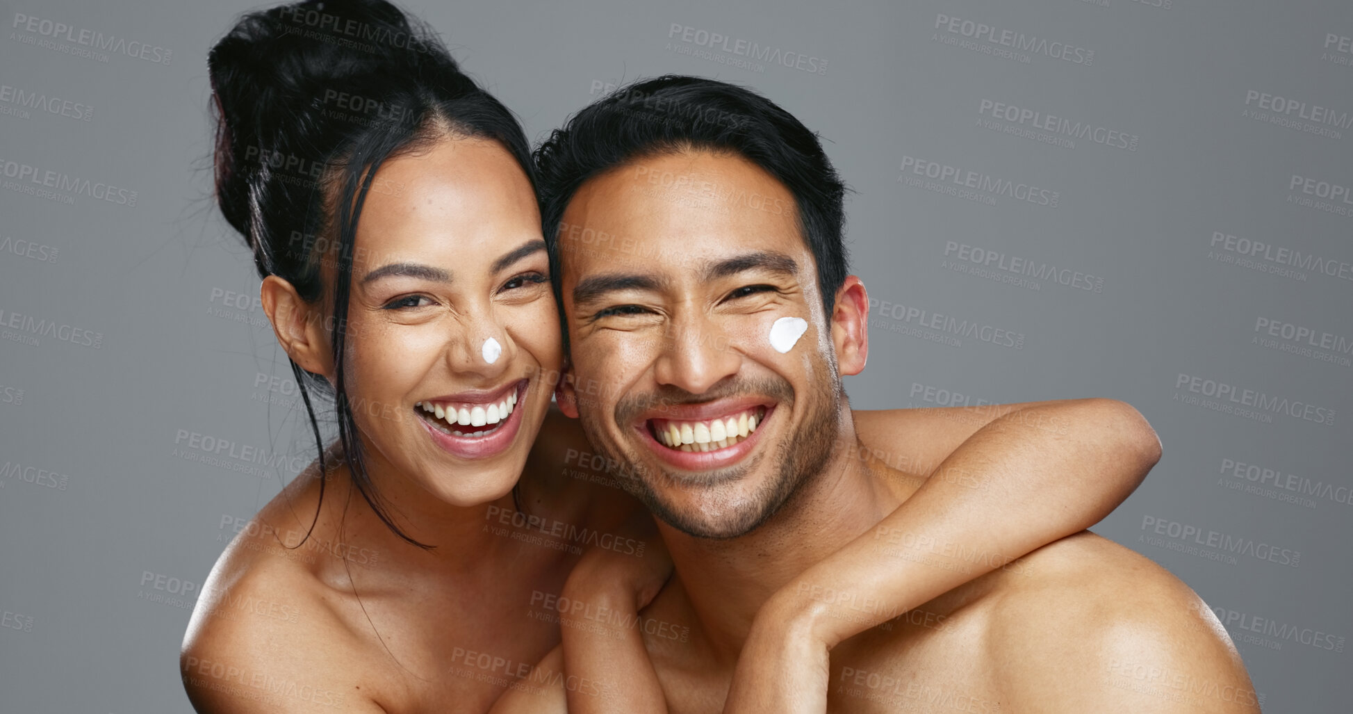 Buy stock photo Couple, smile and love for skincare, care and portrait with moisturizer in studio by gray background. Happy people, dermatology and hug for cosmetics, hydration and creme or love for skin treatment