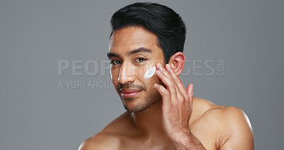 Face, cream and man with skincare, cosmetics and dermatology on a grey studio background. Portrait, person and model with creme, beauty or luxury treatment with grooming, shine or glow with aesthetic