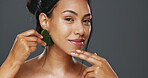 Woman, guasha and skincare for massage, facial and portrait or smile in studio by gray background. Happy model, cosmetics and dermatology in technique for beauty, self love and natural glow by tool